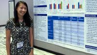 resident standing by research poster